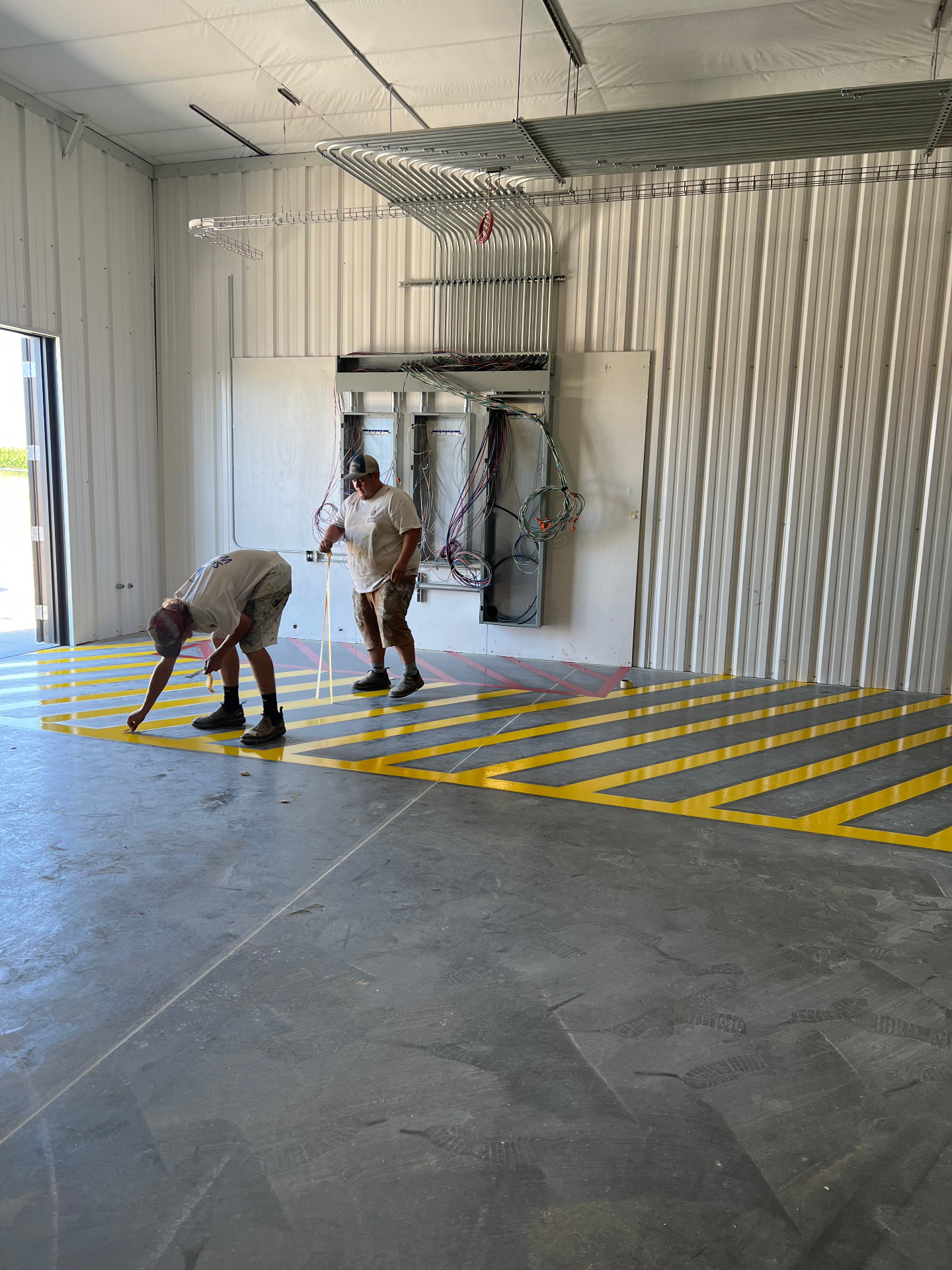 Crew applying yellow safety floor striping in commercial warehouse